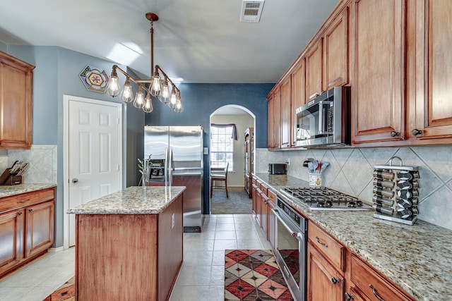 kitchen with visible vents, tasteful backsplash, a center island, stainless steel appliances, and arched walkways