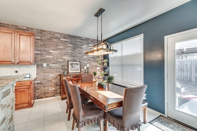 dining space with light tile patterned floors and brick wall