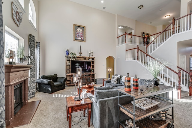 living area featuring stairway, arched walkways, a fireplace, and carpet flooring