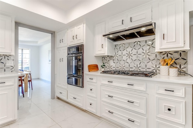 kitchen with a warming drawer, marble finish floor, under cabinet range hood, light countertops, and stainless steel gas cooktop