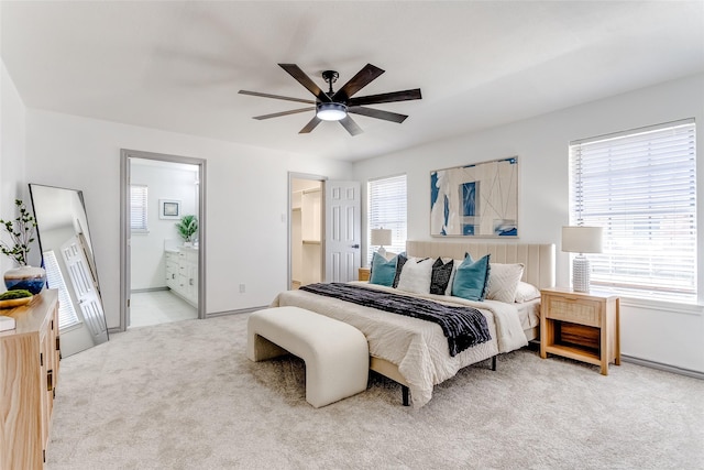 bedroom featuring carpet, ensuite bath, and a ceiling fan