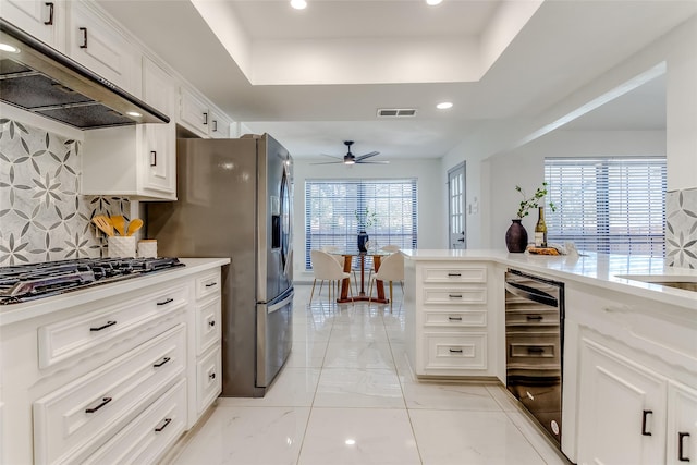 kitchen with under cabinet range hood, visible vents, black gas cooktop, and a tray ceiling