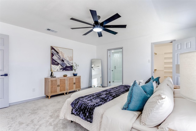 carpeted bedroom featuring visible vents, connected bathroom, a walk in closet, baseboards, and a ceiling fan