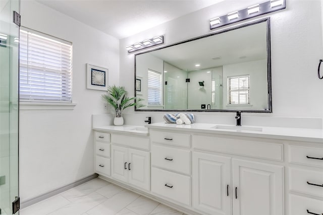 full bath with a sink, marble finish floor, a stall shower, and double vanity