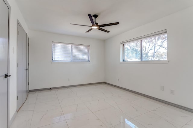 unfurnished bedroom featuring marble finish floor, baseboards, and ceiling fan