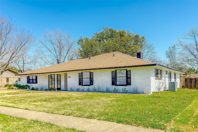 single story home featuring brick siding, central air condition unit, a chimney, and a front lawn