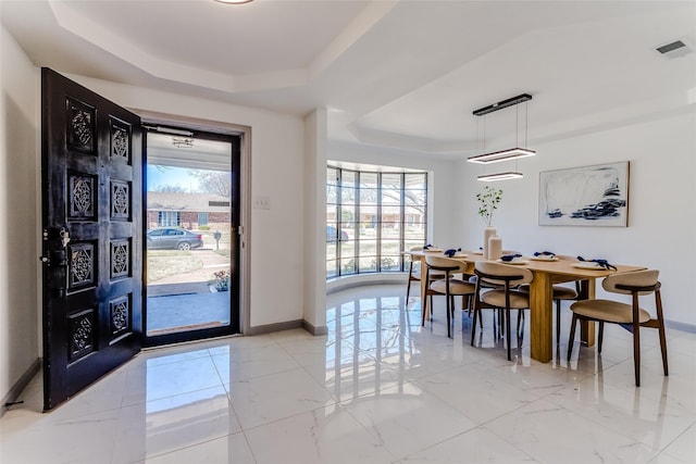 dining area with a tray ceiling, visible vents, baseboards, and a wealth of natural light