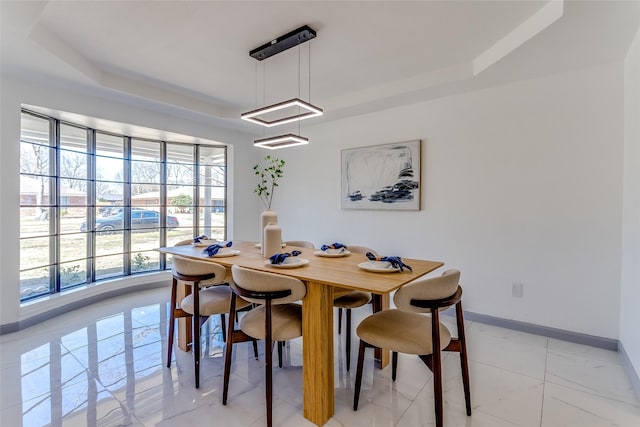 dining space with baseboards and a tray ceiling