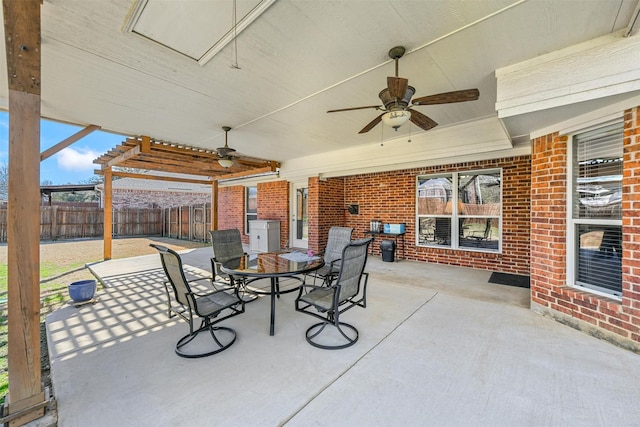 view of patio with ceiling fan, outdoor dining space, and fence