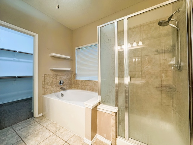 full bathroom featuring tile patterned floors, a shower stall, a bath, and a walk in closet