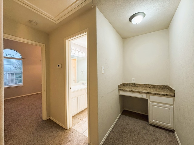 unfurnished office featuring baseboards, light carpet, and built in desk