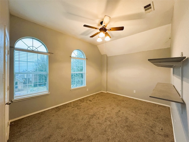 unfurnished room with a ceiling fan, visible vents, baseboards, lofted ceiling, and carpet flooring