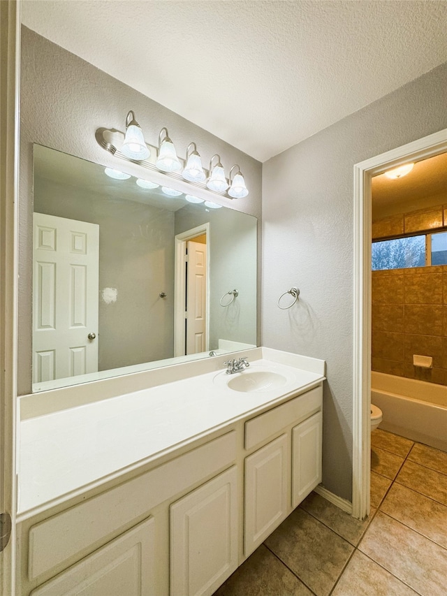 full bathroom featuring tile patterned flooring, toilet, vanity, a bath, and a textured ceiling