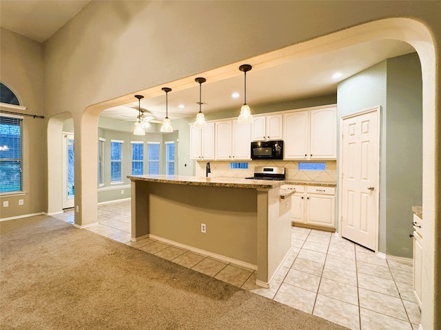 kitchen featuring ceiling fan, black microwave, light tile patterned floors, light carpet, and arched walkways