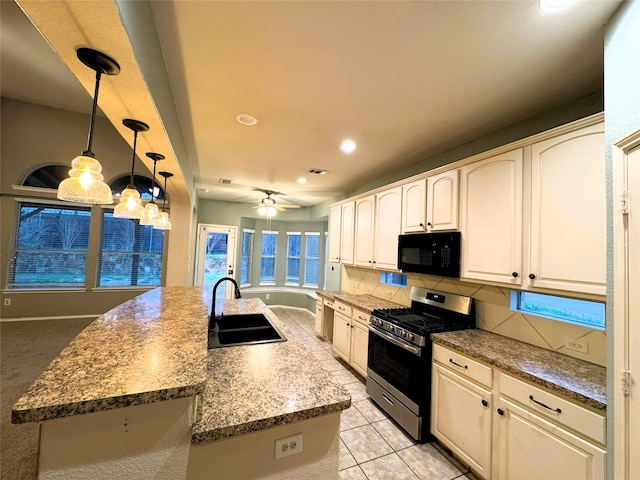 kitchen featuring gas stove, ceiling fan, a sink, black microwave, and tasteful backsplash