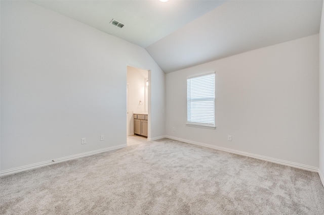 spare room with visible vents, light colored carpet, baseboards, and lofted ceiling