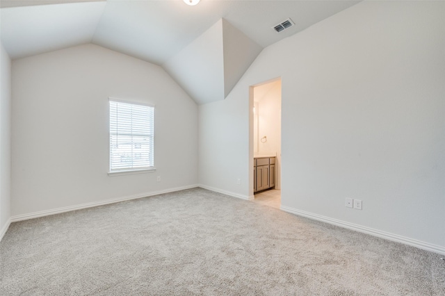 interior space featuring light carpet, visible vents, baseboards, and vaulted ceiling