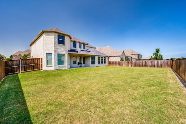 rear view of property with a yard and a fenced backyard