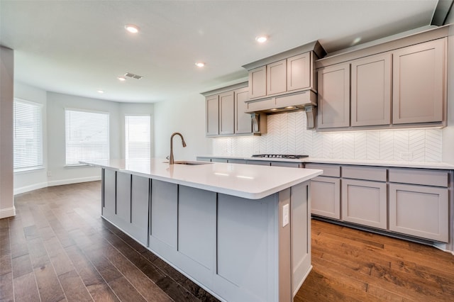 kitchen with visible vents, gray cabinetry, a sink, gas cooktop, and custom exhaust hood