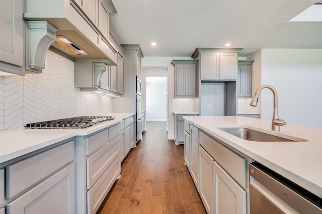 kitchen featuring light countertops, hardwood / wood-style floors, gray cabinets, stainless steel appliances, and a sink