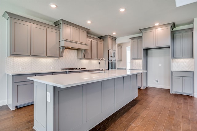 kitchen with a kitchen island with sink, gray cabinets, stainless steel appliances, and a sink