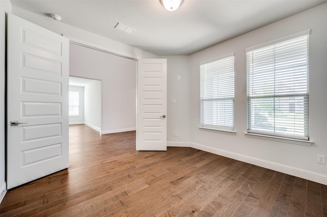 unfurnished room featuring visible vents, baseboards, and wood finished floors