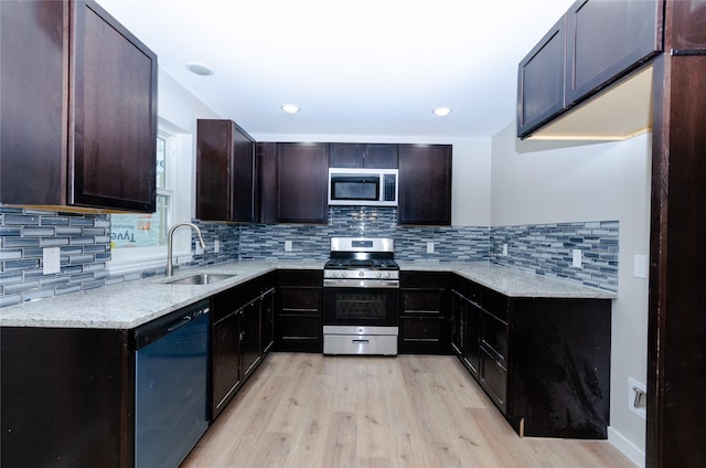 kitchen featuring light stone counters, stainless steel appliances, light wood-type flooring, and a sink