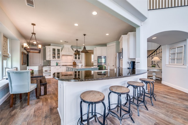 kitchen with premium range hood, backsplash, wood finished floors, and baseboards