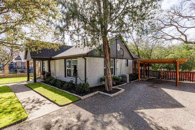 view of side of property featuring brick siding, a shingled roof, fence, central AC, and a yard