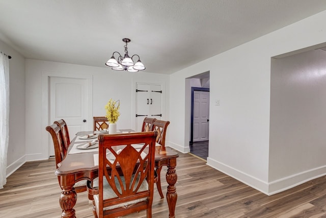 dining room with a notable chandelier, light wood-type flooring, and baseboards