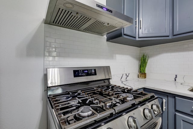 kitchen with backsplash, light stone countertops, extractor fan, and stainless steel gas range