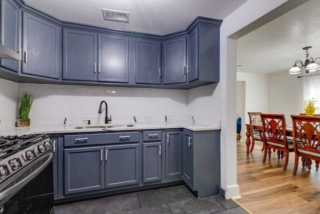 kitchen featuring gas stove, visible vents, a sink, a notable chandelier, and tasteful backsplash