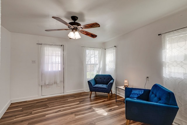 sitting room featuring baseboards, wood finished floors, and a ceiling fan