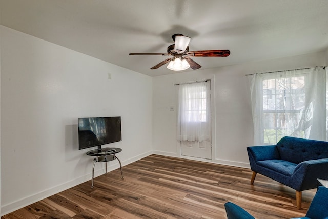 sitting room with a ceiling fan, wood finished floors, and baseboards