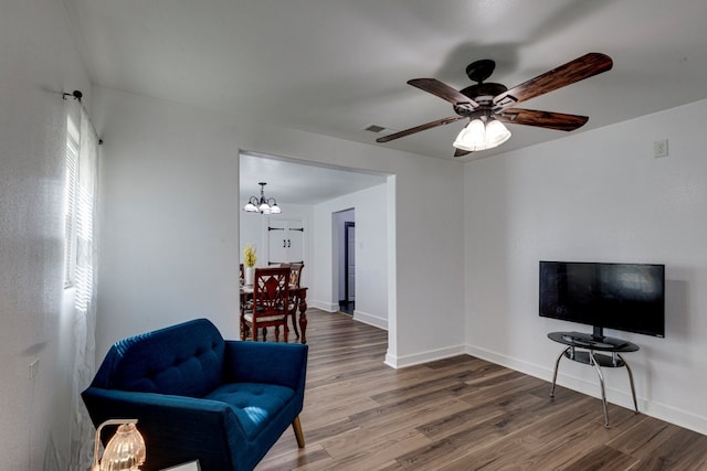 sitting room featuring visible vents, ceiling fan with notable chandelier, baseboards, and wood finished floors