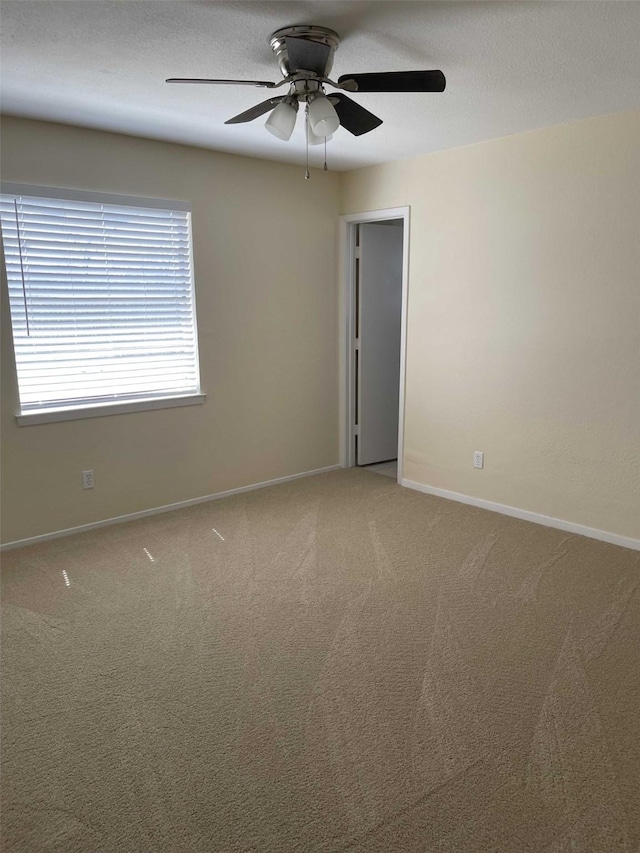 carpeted empty room featuring a textured ceiling, baseboards, and ceiling fan