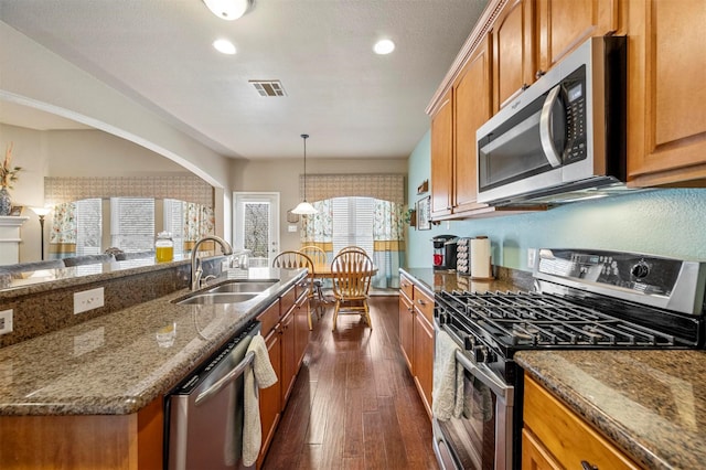 kitchen featuring visible vents, dark wood-type flooring, a sink, stainless steel appliances, and brown cabinetry