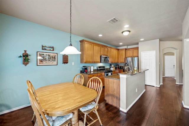 kitchen featuring dark wood finished floors, arched walkways, visible vents, and stainless steel appliances