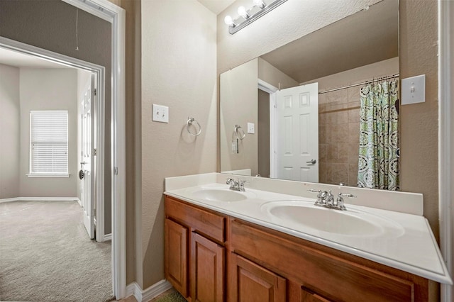 bathroom featuring double vanity, a shower with shower curtain, baseboards, and a sink