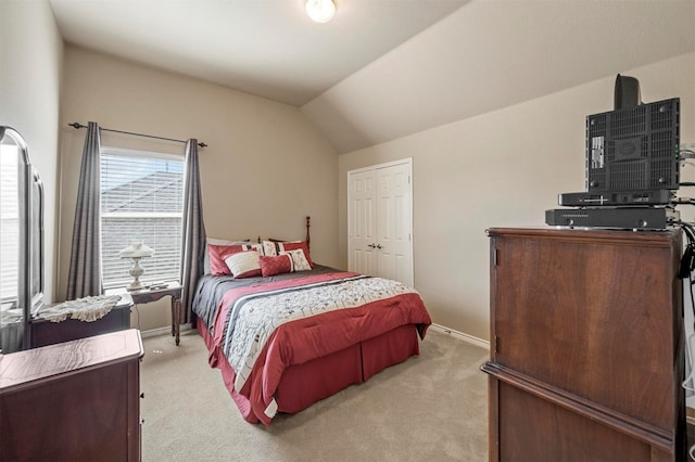 bedroom with vaulted ceiling, light colored carpet, baseboards, and a closet