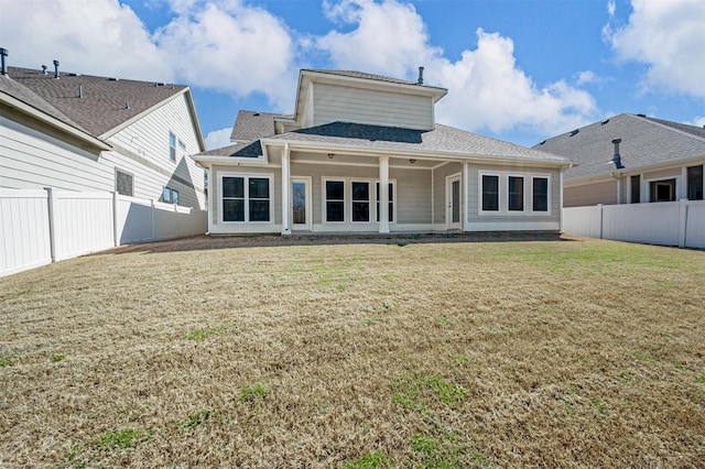 rear view of property with a lawn, roof with shingles, and a fenced backyard