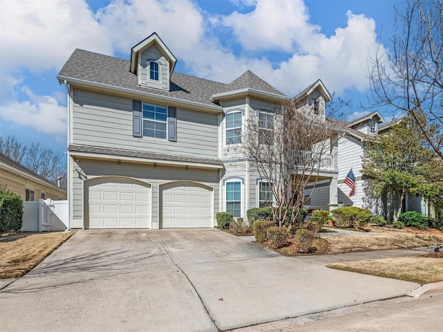 view of front facade featuring a gate, fence, driveway, an attached garage, and a shingled roof