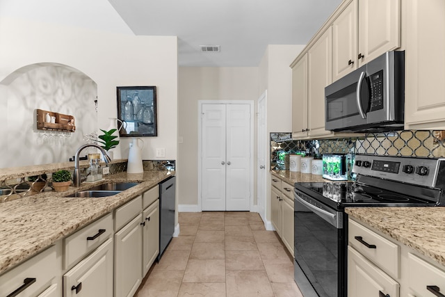 kitchen featuring visible vents, light stone countertops, decorative backsplash, appliances with stainless steel finishes, and a sink