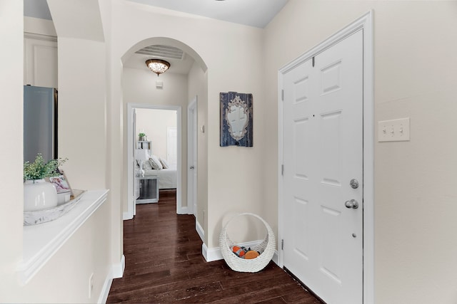 foyer with baseboards, arched walkways, and dark wood-type flooring