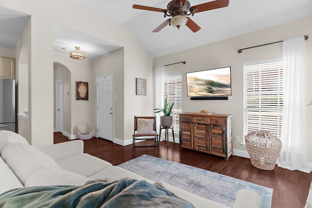 living room with lofted ceiling, a ceiling fan, wood finished floors, arched walkways, and baseboards