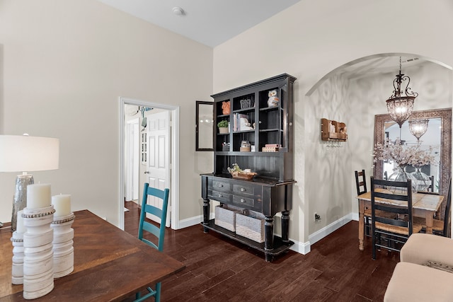 dining area featuring baseboards, arched walkways, wood finished floors, and a chandelier