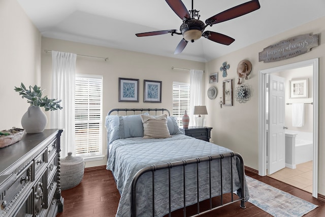 bedroom with baseboards, multiple windows, ensuite bath, and dark wood finished floors