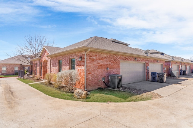 view of property exterior featuring brick siding, a shingled roof, central air condition unit, a garage, and driveway