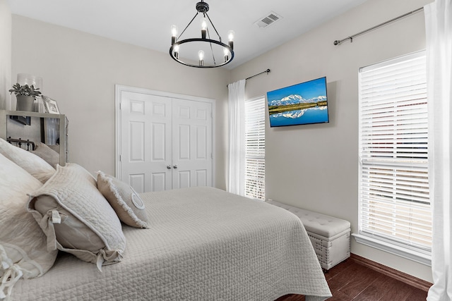 bedroom featuring wood finished floors, visible vents, a closet, multiple windows, and a chandelier