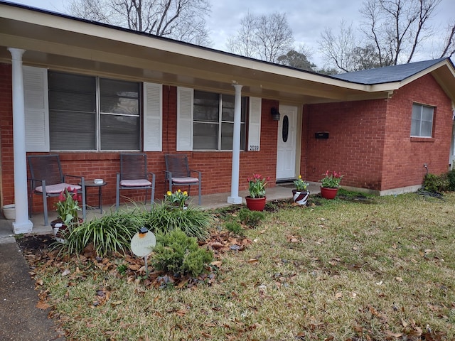 view of front of home with brick siding, a porch, and a front yard